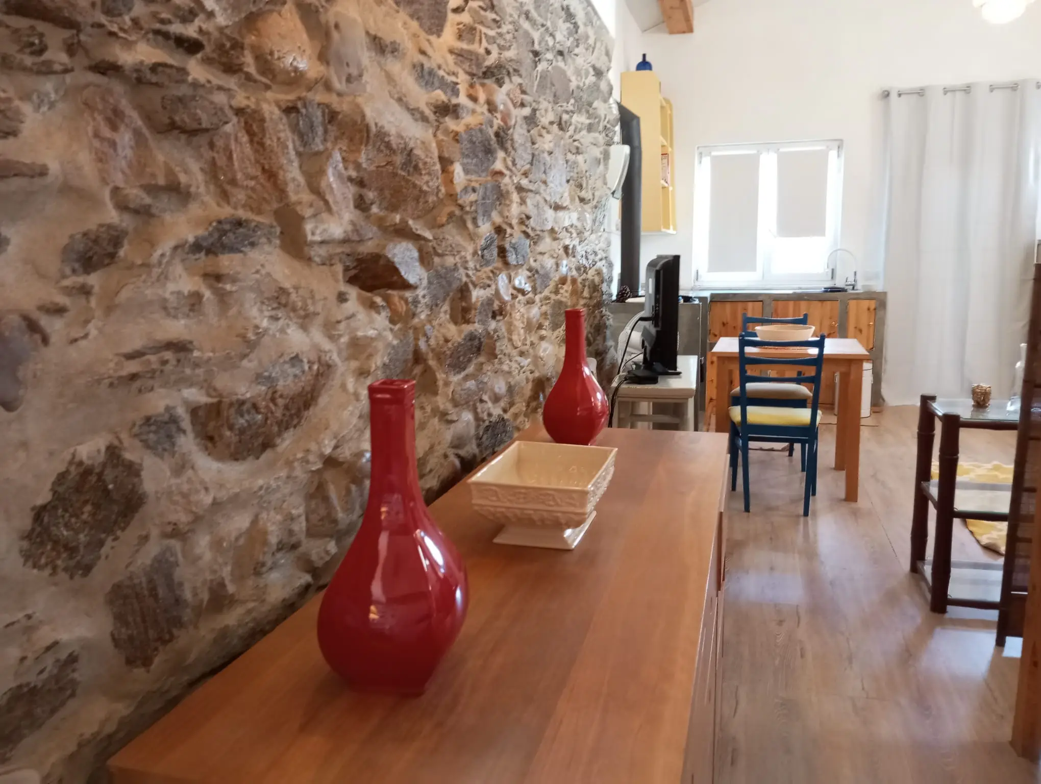 Pormenor da parede de pedra da Casa Pequena, com jarras vermelhas sobre o aparador