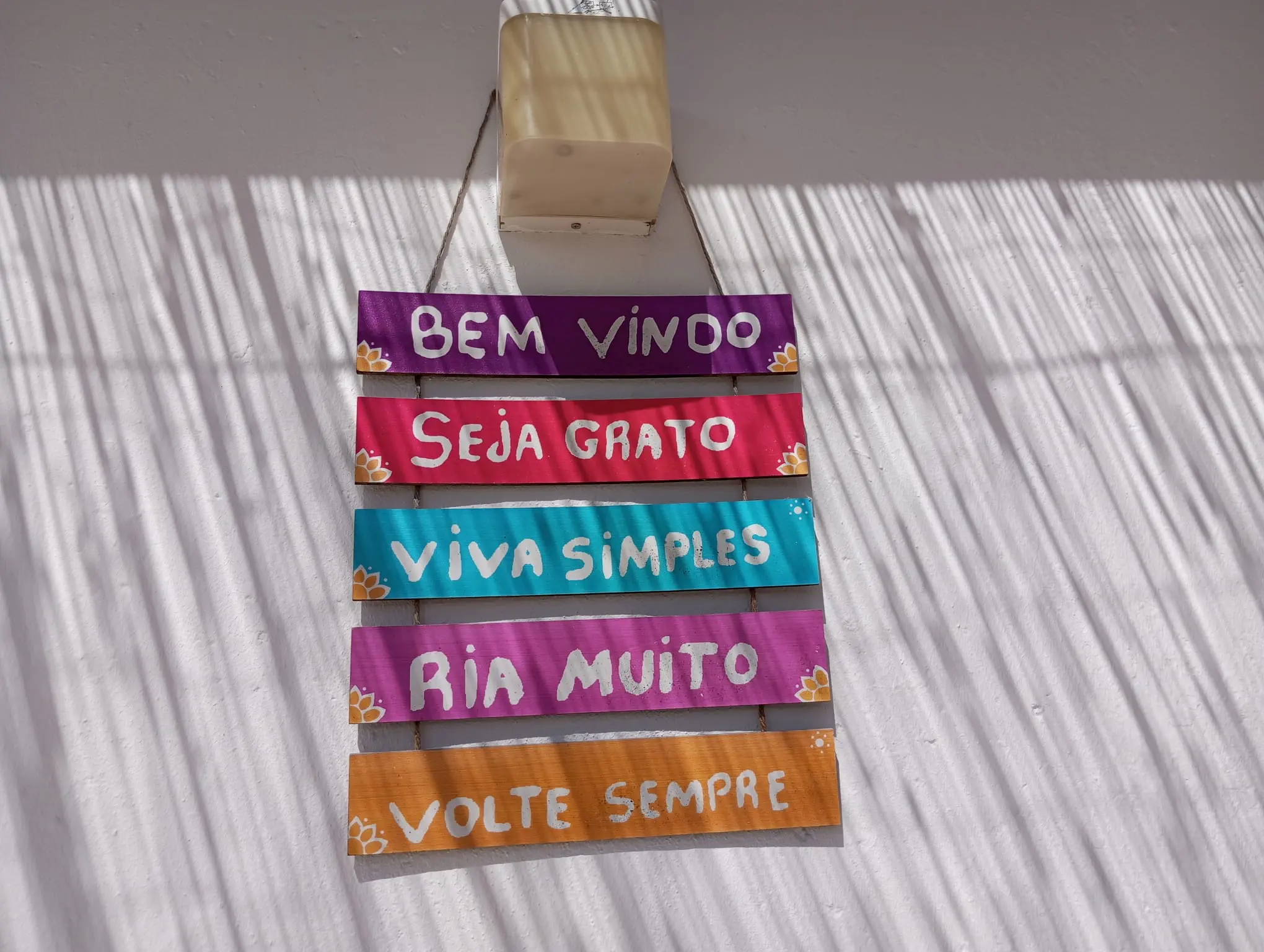 Placa de madeira colorida à entrada: Bem Vindo, Seja Grato, Viva Simples, Ria Muito, Volte Sempre
