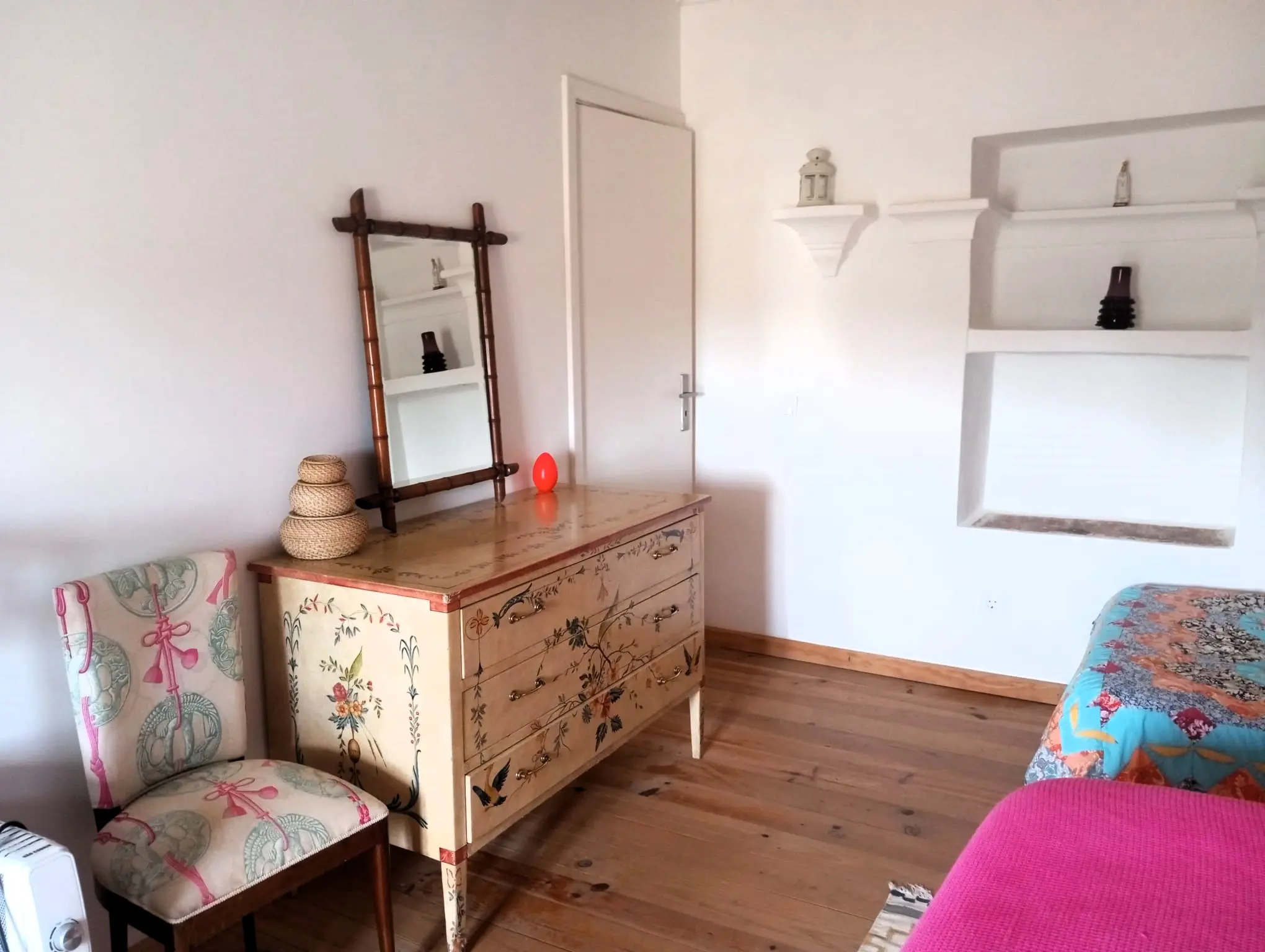 Cómoda antiga pintada e têxteis bohemian num quarto luminoso