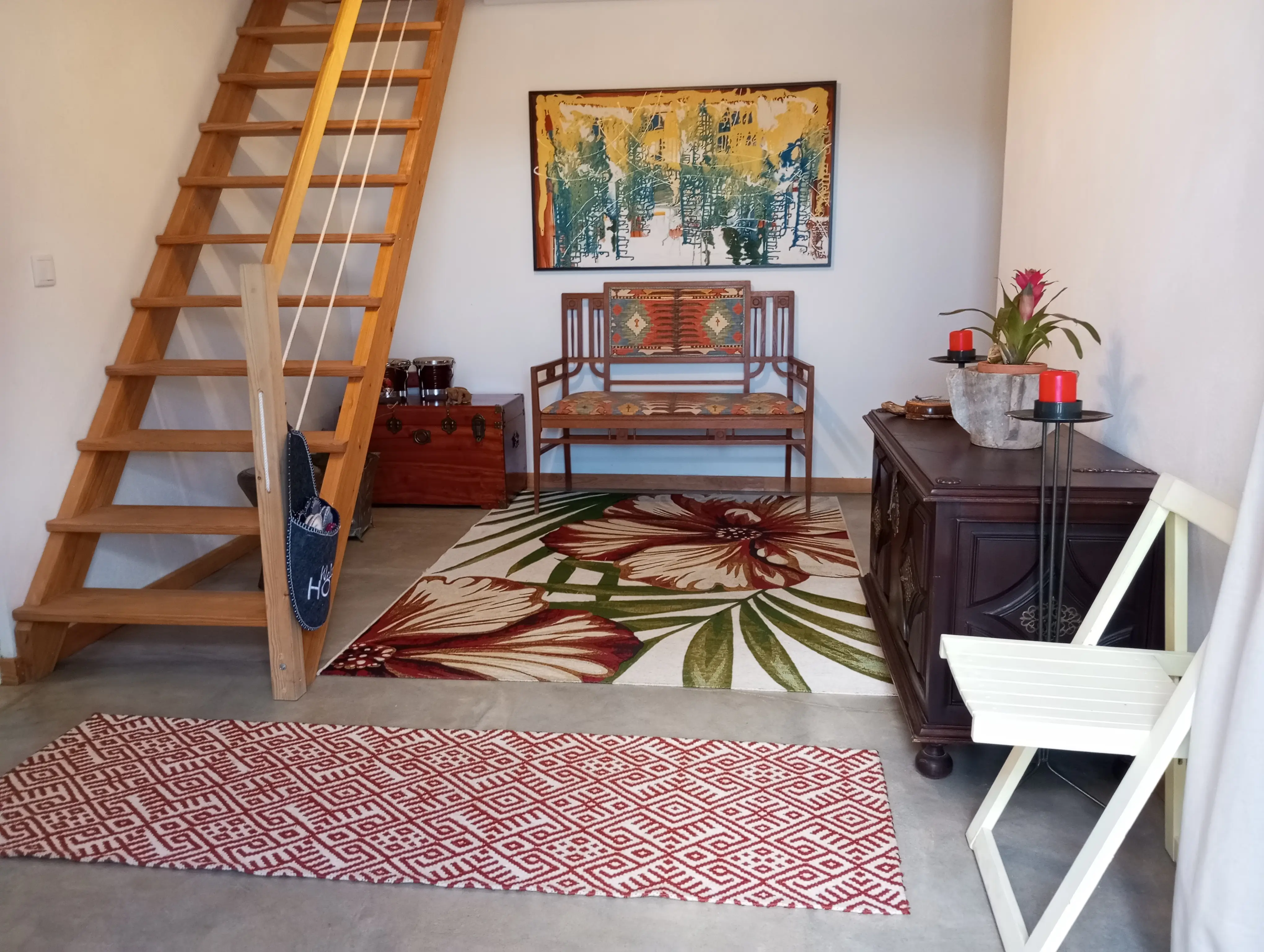 Hall de entrada da Casa Principal, com as escadas de madeira para o quarto do primeiro piso e tapete de flores