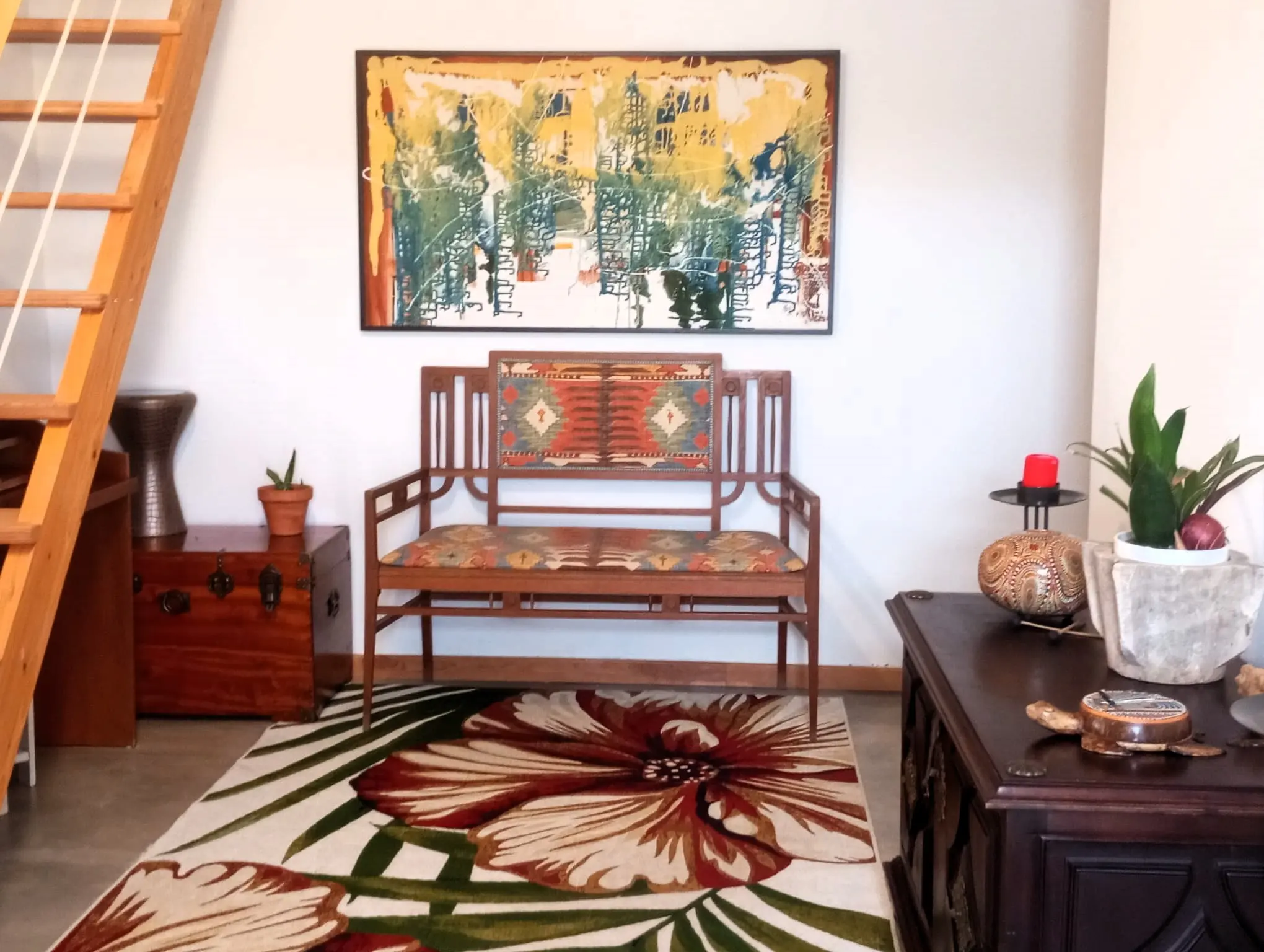 Hall de entrada da Casa Principal, com escada de madeira, tapete de flores e banco de madeira trabalhada