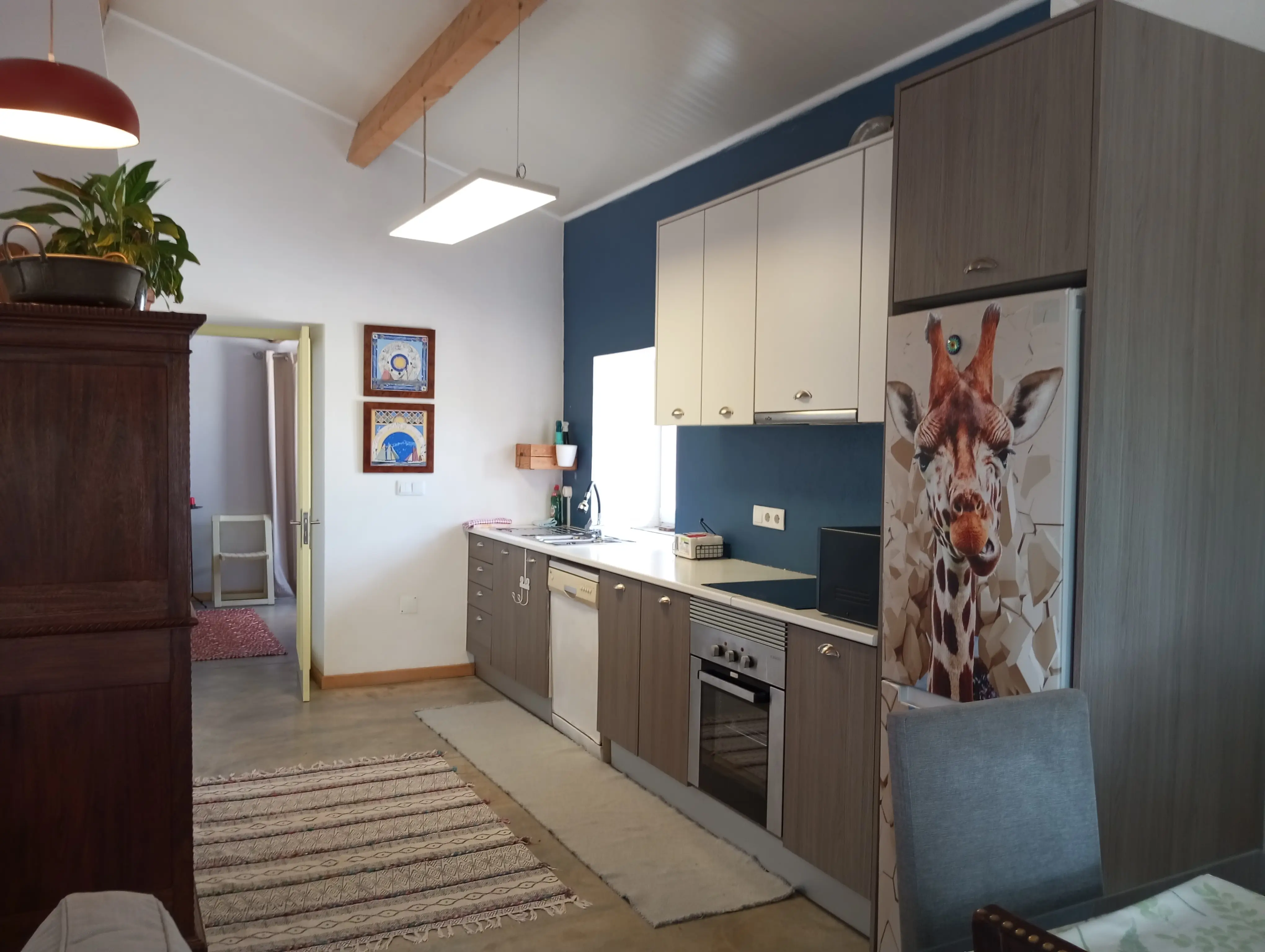Cozinha da Casa Principal, totalmente equipada, com parede azul, máquina de lavar loiça e forno